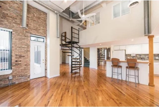 interior space with light wood-style floors, a high ceiling, stairway, and a wealth of natural light