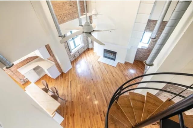 interior space with a glass covered fireplace, wood finished floors, and a ceiling fan