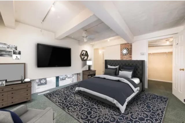 bedroom with a spacious closet, carpet flooring, beam ceiling, and track lighting