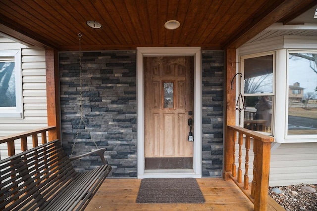 entrance to property with a porch and stone siding