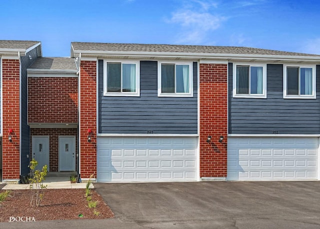 multi unit property featuring brick siding, driveway, and an attached garage