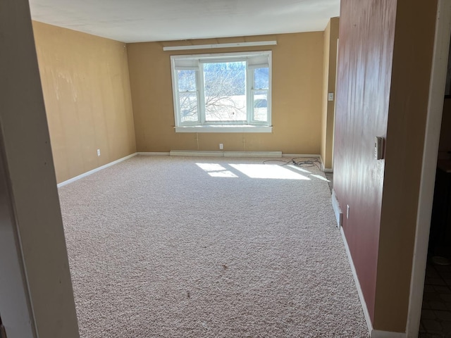 spare room with a baseboard heating unit, carpet flooring, and baseboards