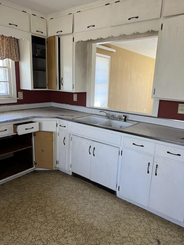 kitchen with light floors, a sink, and white cabinetry