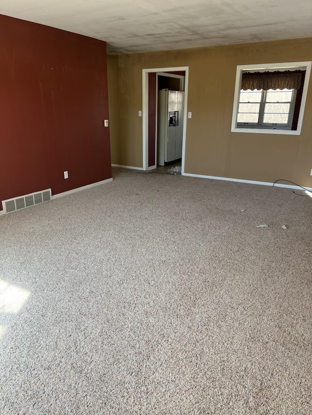 carpeted spare room featuring visible vents and baseboards