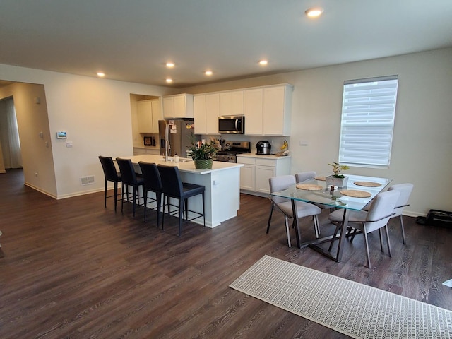 kitchen with appliances with stainless steel finishes, a kitchen island with sink, visible vents, white cabinets, and recessed lighting