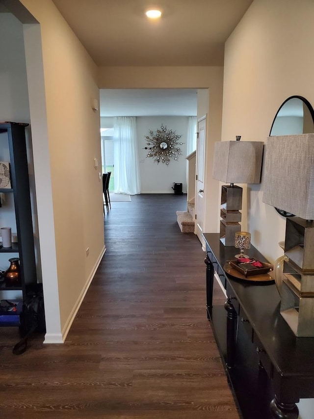 corridor featuring baseboards and dark wood-style flooring
