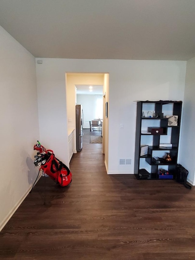 hall featuring dark wood-type flooring, baseboards, and visible vents