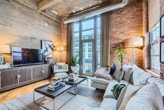 living area featuring brick wall, a high ceiling, and wood finished floors