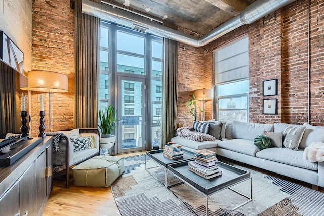 interior space featuring brick wall, light wood-style flooring, and a high ceiling