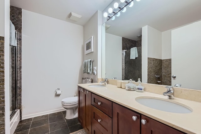 bathroom featuring tiled shower, a sink, toilet, and double vanity