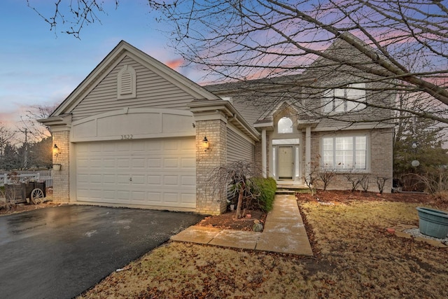 view of front facade with brick siding, an attached garage, and aphalt driveway