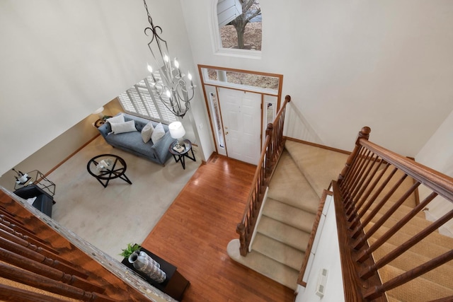 foyer entrance featuring a chandelier, a high ceiling, wood finished floors, baseboards, and stairs