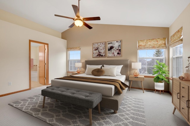 bedroom with lofted ceiling, light colored carpet, a ceiling fan, ensuite bath, and baseboards