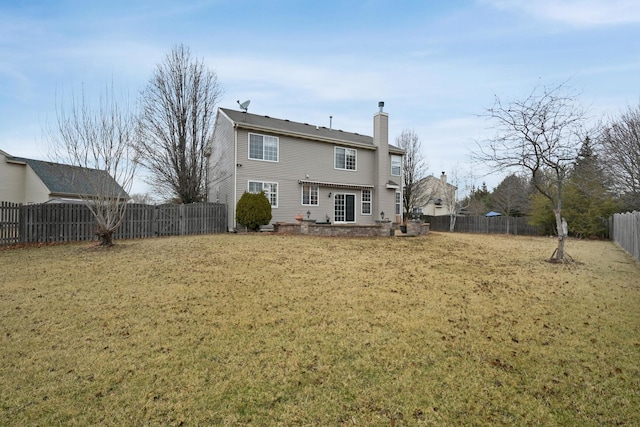 back of property featuring a fenced backyard, a chimney, and a yard