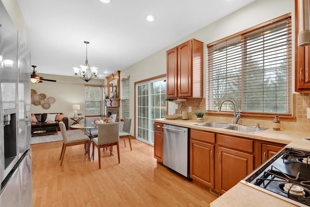 kitchen with a sink, stainless steel appliances, light countertops, and decorative light fixtures