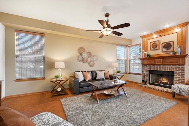 living room featuring a fireplace, a ceiling fan, and baseboards