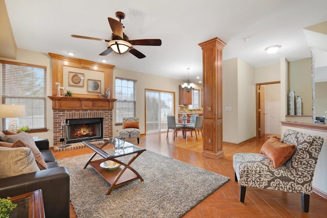 living room featuring ceiling fan with notable chandelier, a fireplace, and ornate columns