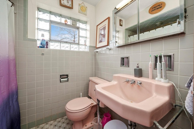 bathroom featuring toilet, a sink, tile walls, and a shower with shower curtain