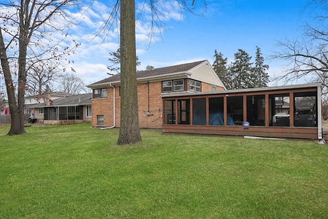 back of property with a yard, brick siding, and a sunroom