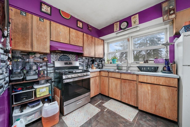 kitchen with gas range, brown cabinets, light countertops, under cabinet range hood, and a sink