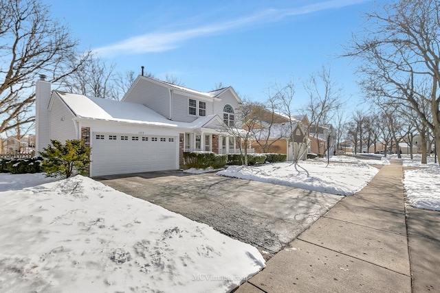 view of front of home with an attached garage, a chimney, and aphalt driveway