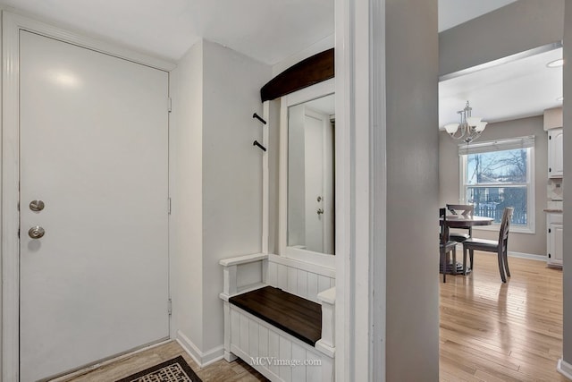 mudroom with a chandelier, baseboards, and light wood finished floors