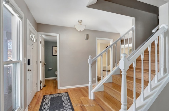 foyer entrance with baseboards, stairway, and light wood-style floors