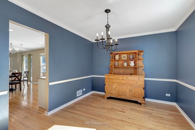 dining space with crown molding, a notable chandelier, light wood-style flooring, and baseboards