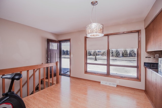 dining space featuring light wood-style floors, a chandelier, visible vents, and baseboards