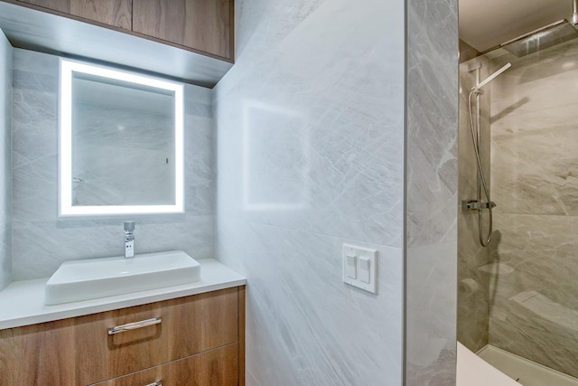 bathroom featuring tile walls, tiled shower, and vanity