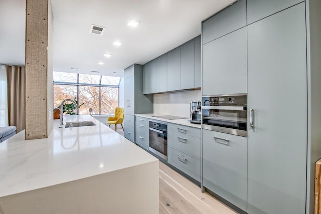 kitchen featuring gray cabinets, visible vents, a sink, modern cabinets, and oven