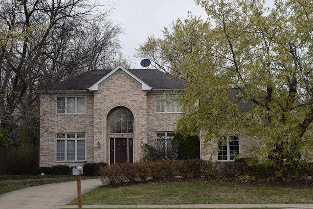 traditional-style house featuring brick siding and a front lawn