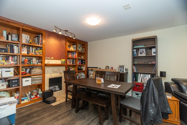 dining room featuring dark wood-style flooring and a tiled fireplace