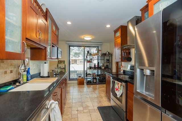 kitchen featuring stainless steel appliances, tasteful backsplash, brown cabinetry, and glass insert cabinets