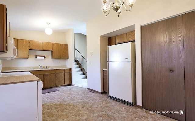 kitchen featuring light countertops, vaulted ceiling, brown cabinetry, a notable chandelier, and white appliances