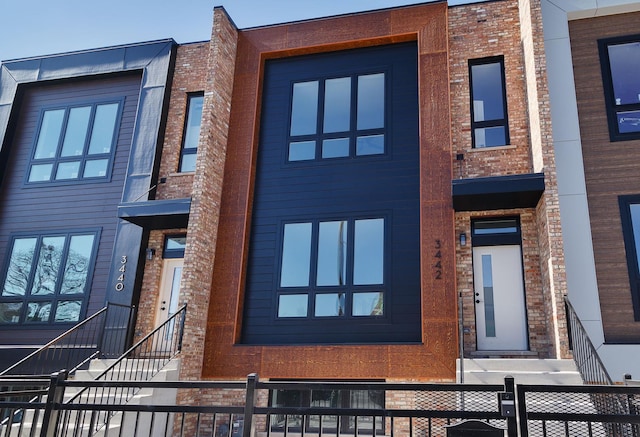 view of front facade featuring fence and brick siding