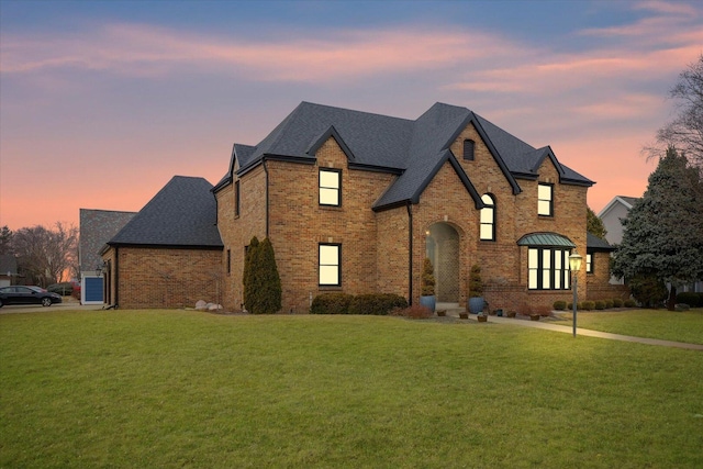 french country style house with brick siding and a front yard