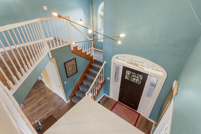 entrance foyer featuring stairway, a towering ceiling, and wood finished floors