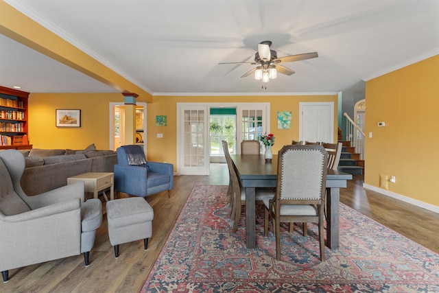 dining room featuring stairs, crown molding, baseboards, and wood finished floors