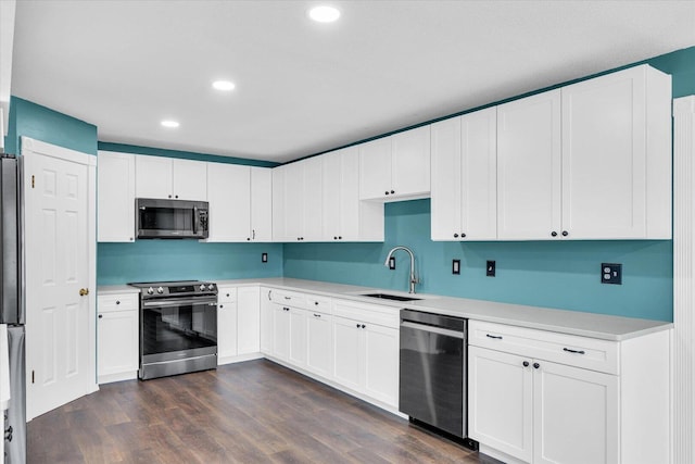 kitchen with light countertops, appliances with stainless steel finishes, dark wood-style flooring, and a sink