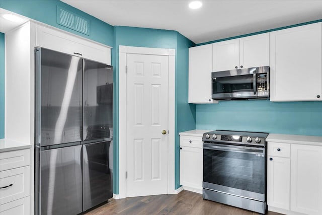 kitchen with visible vents, white cabinets, dark wood finished floors, appliances with stainless steel finishes, and light countertops