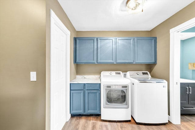 laundry area featuring light wood-type flooring, cabinet space, and washing machine and dryer