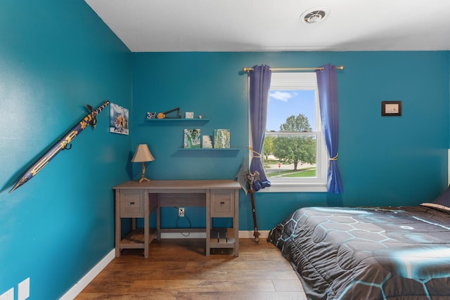 bedroom with visible vents, baseboards, and wood finished floors