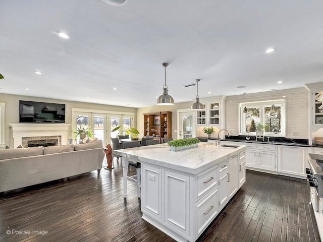 kitchen featuring visible vents, dark wood finished floors, a kitchen island with sink, white cabinetry, and a sink