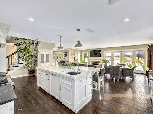 kitchen with dark wood-style flooring, a sink, visible vents, white cabinets, and french doors