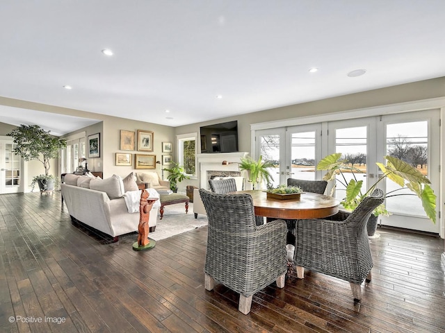 dining space with dark wood-style floors, french doors, a fireplace, and recessed lighting