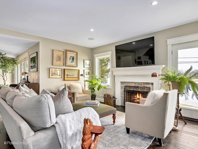 living room featuring a lit fireplace, wood-type flooring, and recessed lighting