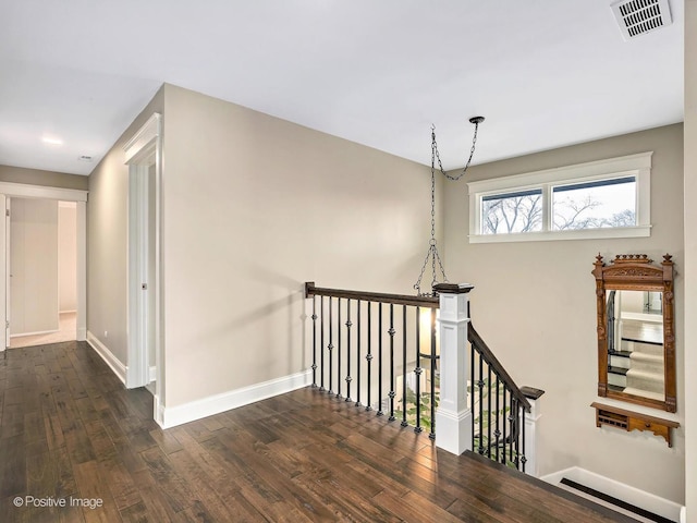 hall featuring an upstairs landing, visible vents, dark wood finished floors, and baseboards