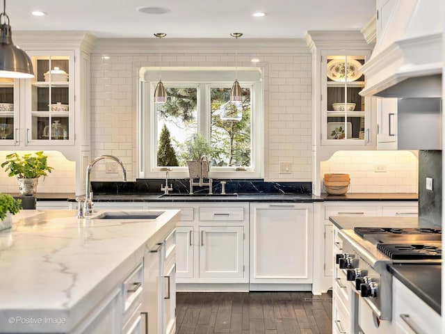 kitchen featuring premium range hood, stainless steel gas stovetop, a sink, and white cabinetry