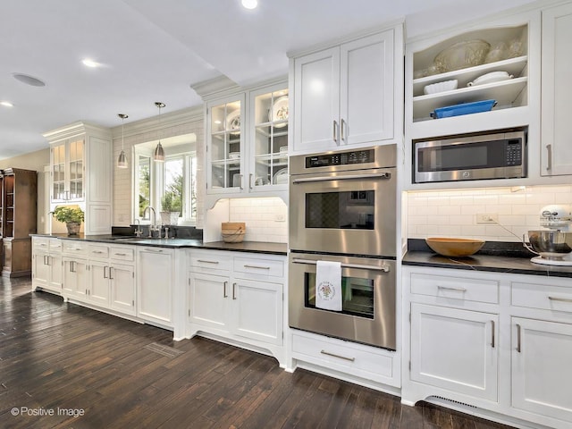 kitchen with dark countertops, dark wood finished floors, stainless steel appliances, and a sink